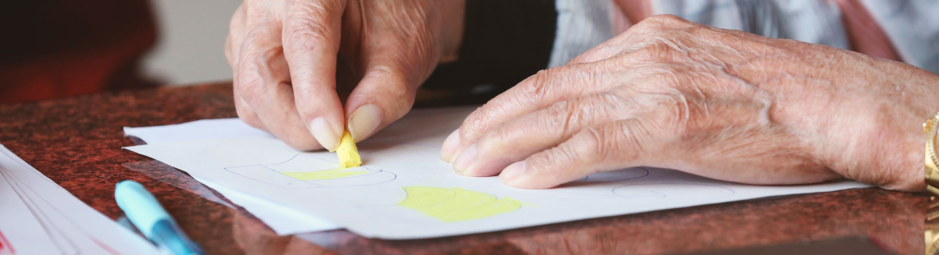 Hände einer Frau beim Malen mit Wachsmalstiften